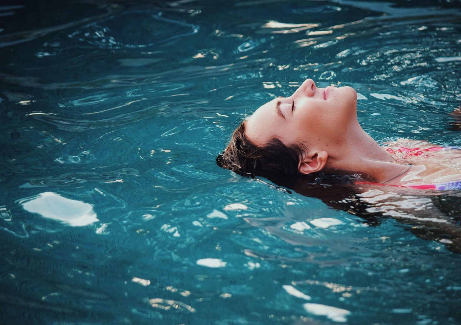 person floating on their back in beautiful blue water looking relaxed and stress-free