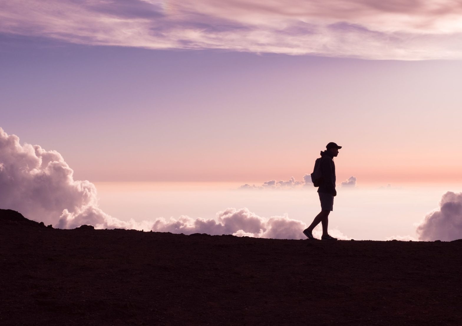 Image shows person walking in a vast outdoor space during sunset looking deep in thought and enjoying all the benefits of walking and walking meditation for their mental health and wellbeing