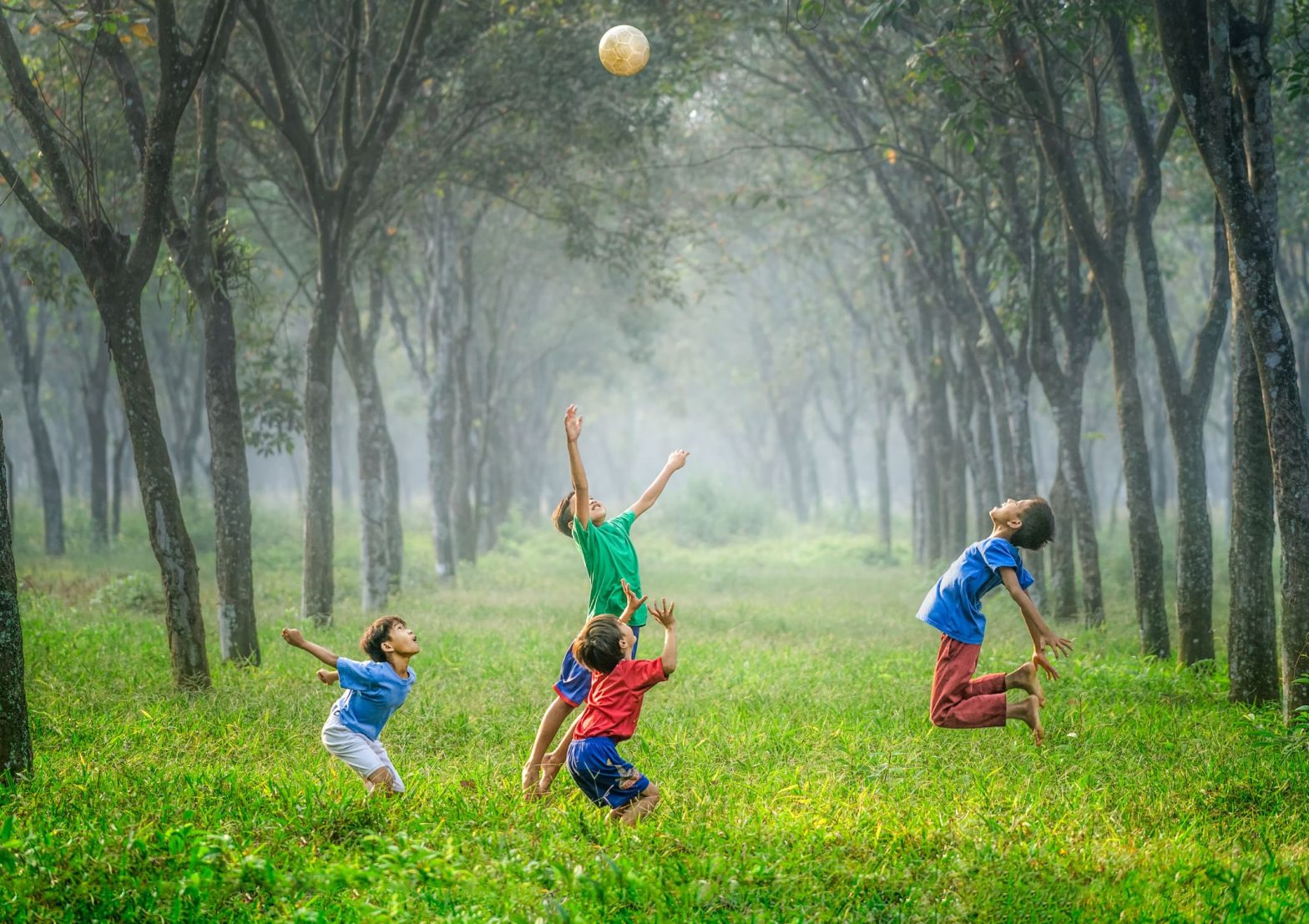 Image shows young children filled with joy and excitement jumping and playing in the woods