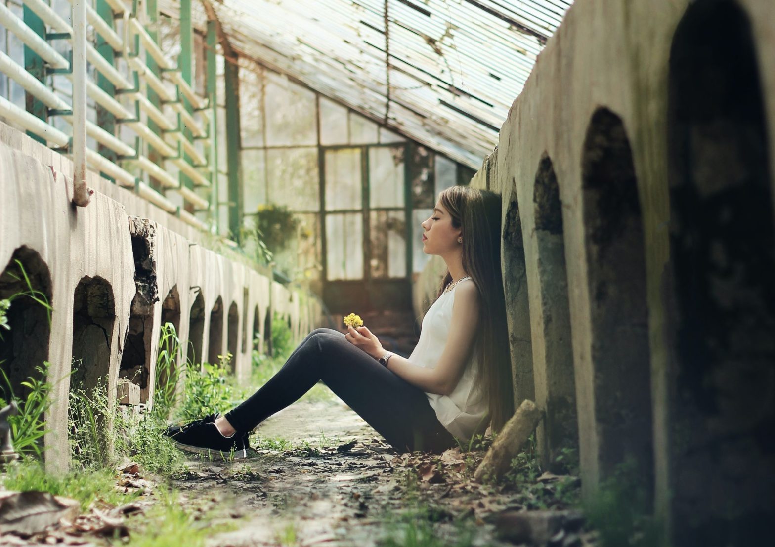 Image shows someone sitting against a wall in a contemplative state