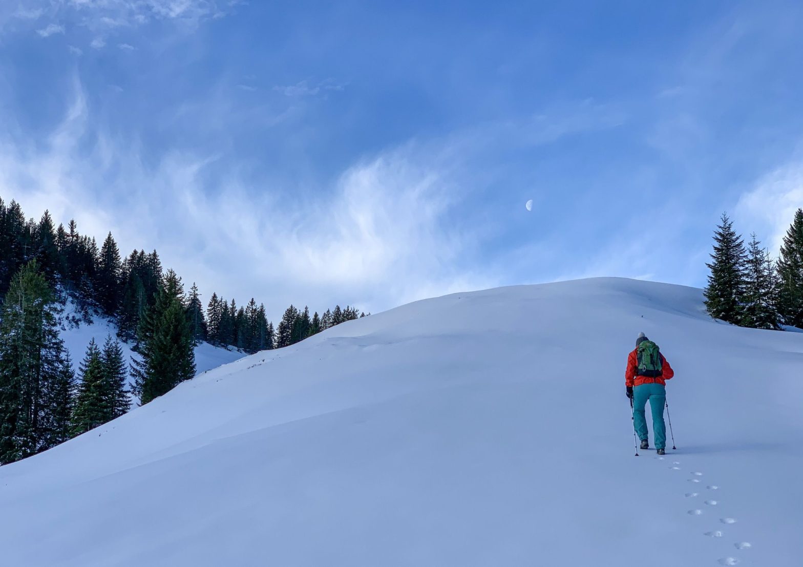Image shows someone climbing a snowy hill with blue skies and fresh air to benefit their mental health and wellbeing