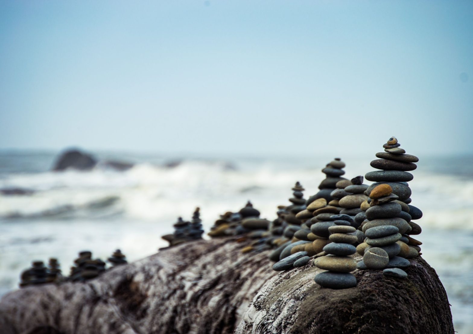 Image shows a series of carefully stacked pebble piles on a cliff beside the sea