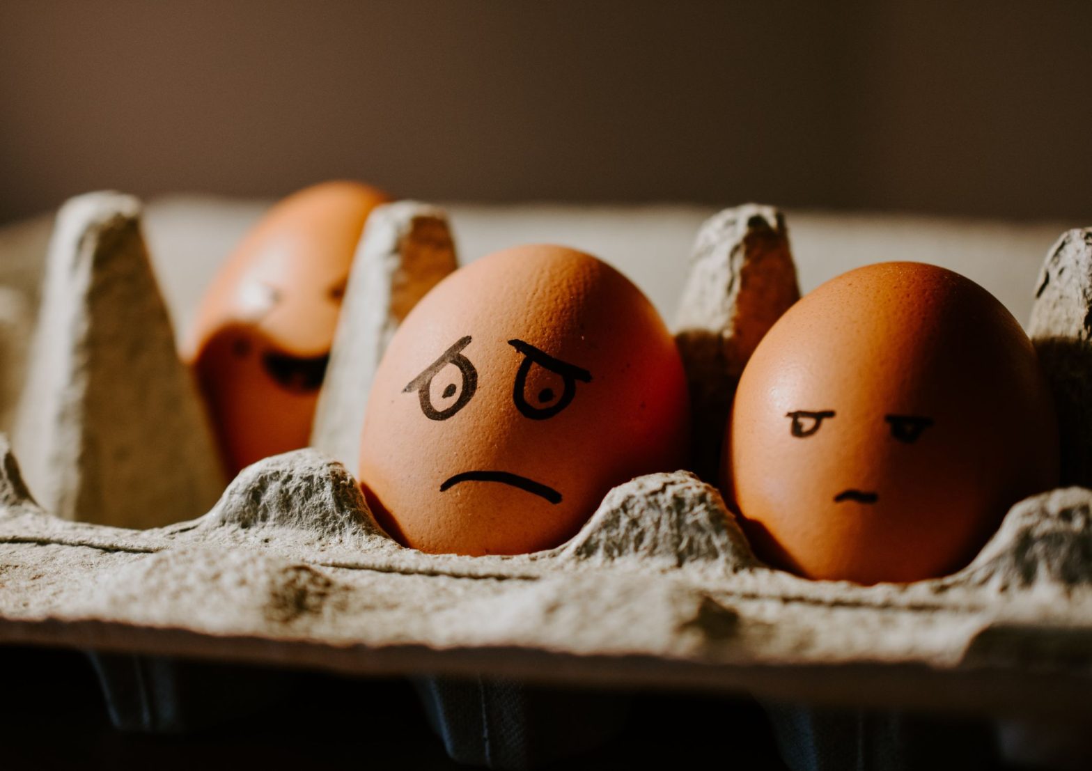 Image shows a box of eggs, two of which have worried looking faces drawn on to them