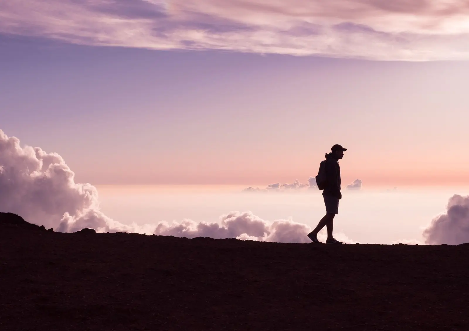 Image shows person walking in a vast outdoor space during sunset looking deep in thought and enjoying all the benefits of walking and walking meditation for their mental health and wellbeing