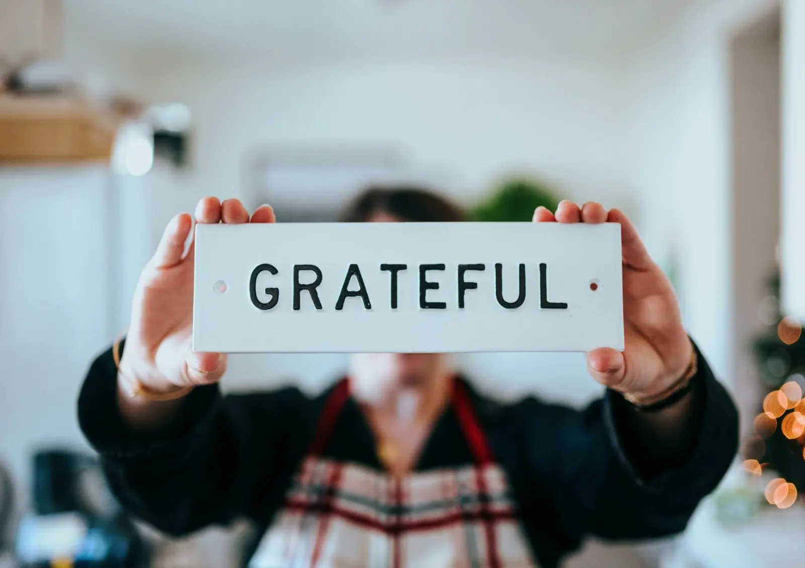 Person holding a sign saying 'grateful' to remind us to express our gratitude to help improve our mental health and wellbeing